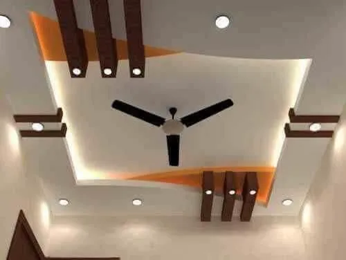 False ceiling in orange and wood tones with downlights and a ceiling fan