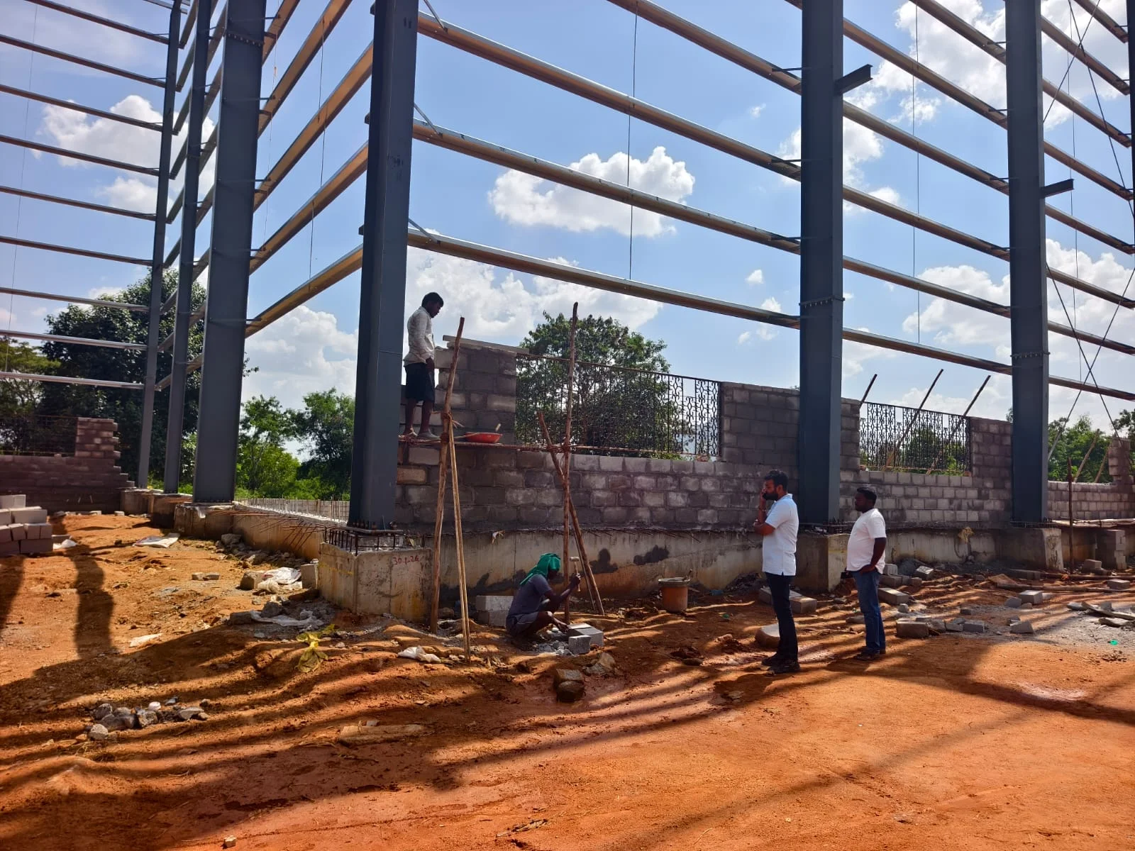 Site team inspecting wall construction inside the steel structure