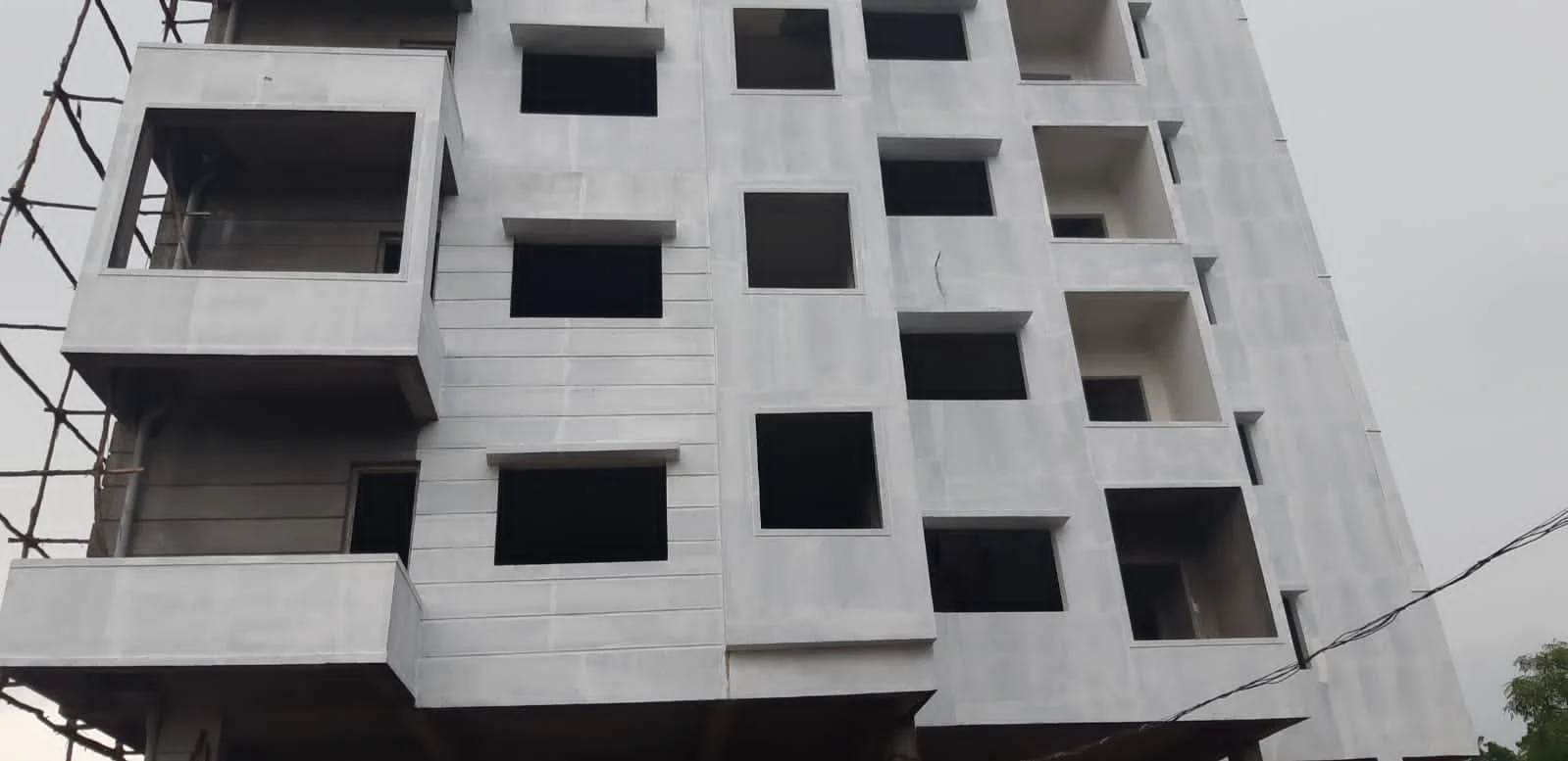 Multi-storey building facade with open windows and balconies during construction